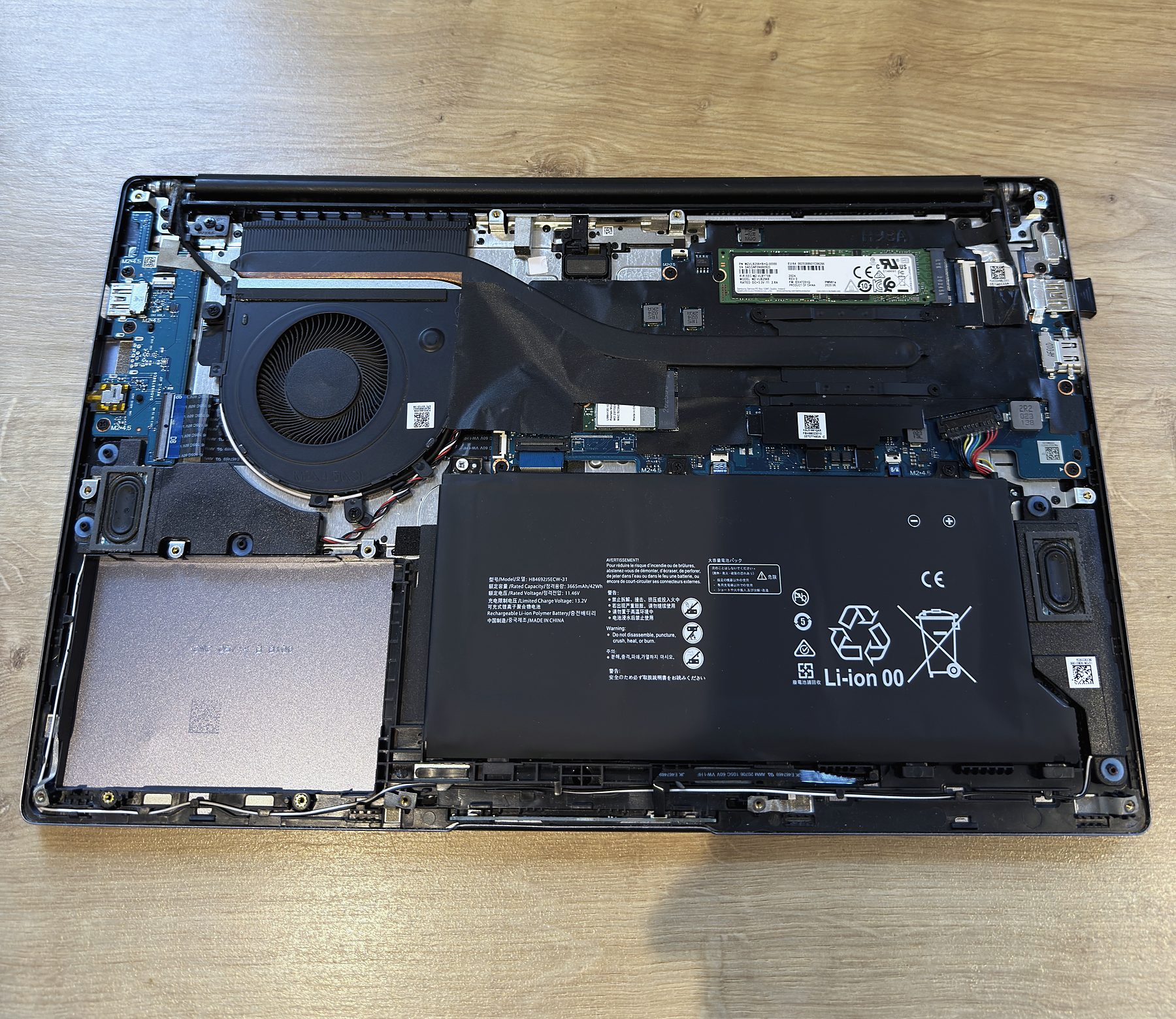 A laptop opened up showing the fan, battery and SSD
