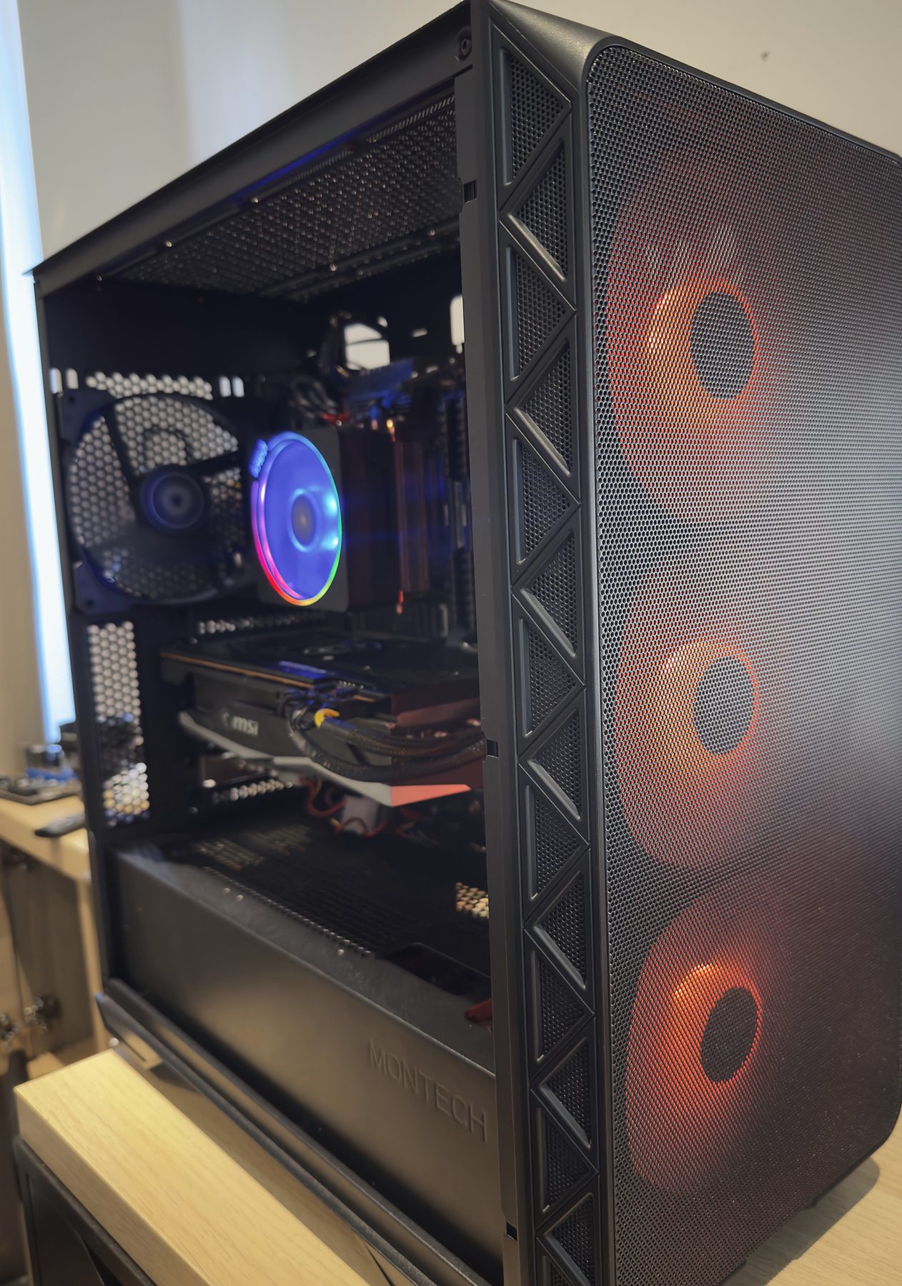 A PC with its side panel open, front fans glowing orange