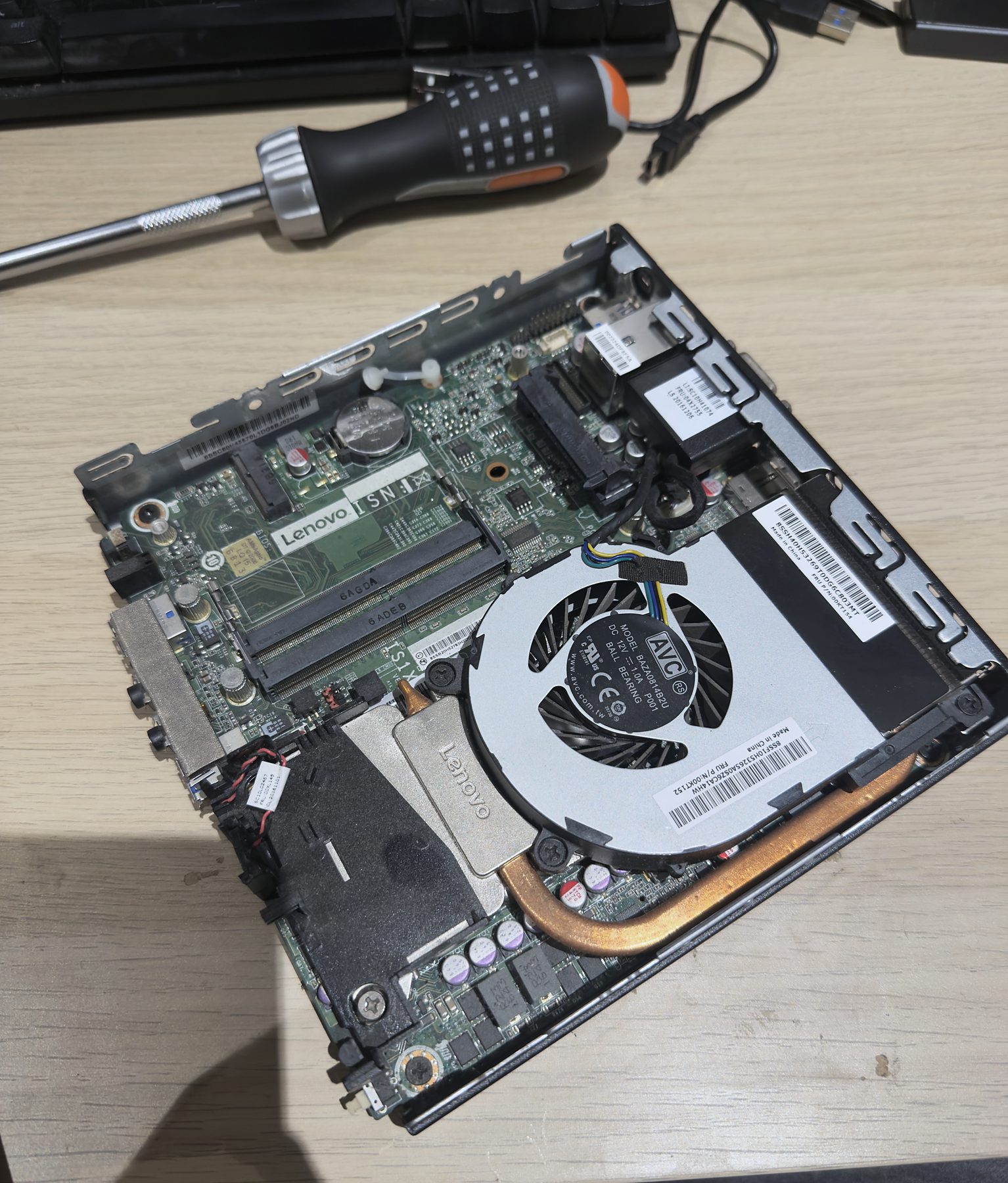 A small Lenovo PC opened up next to a screwdriver