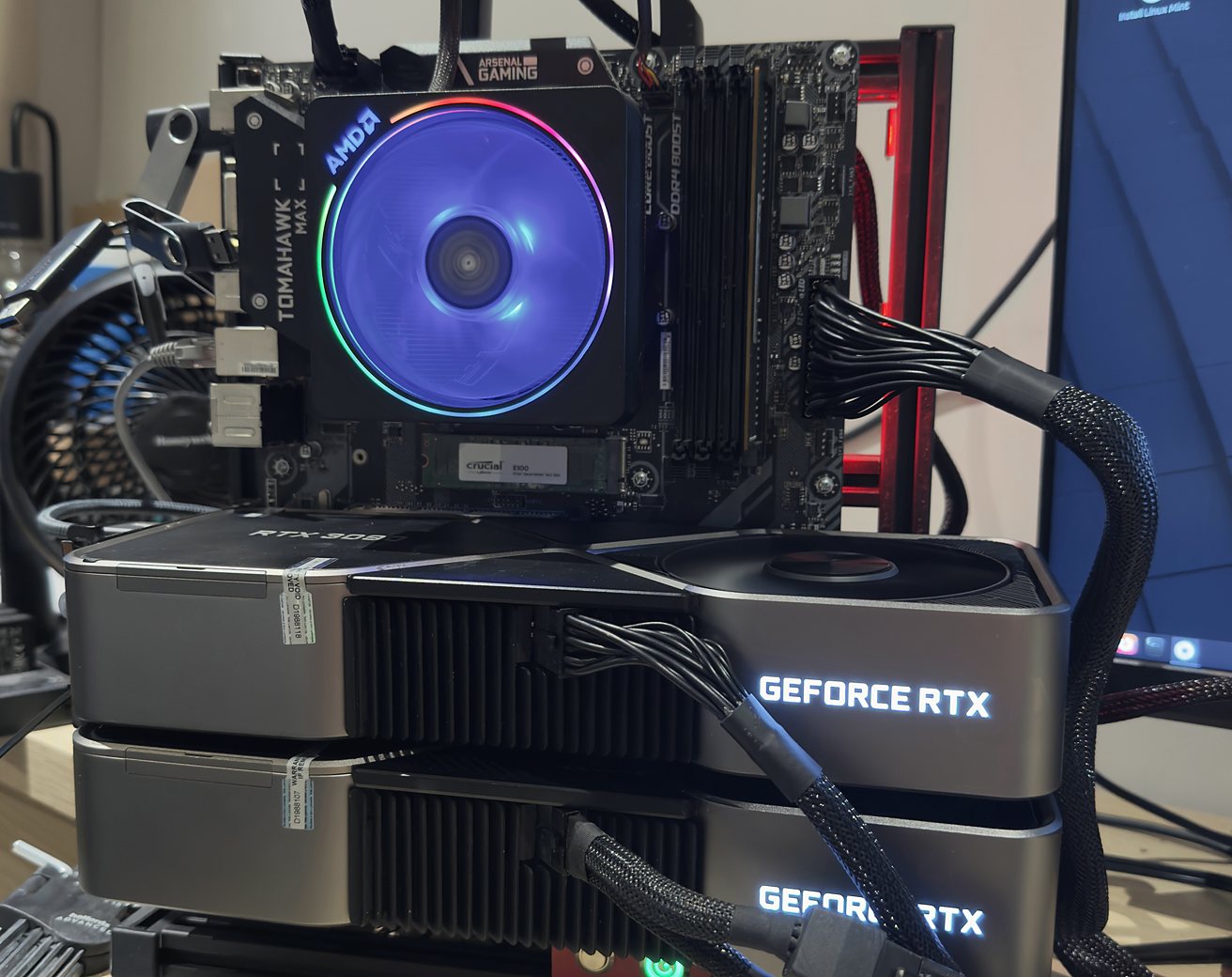 Two RTX 3090 graphics cards stacked on an open test bench with an RGB CPU cooler above